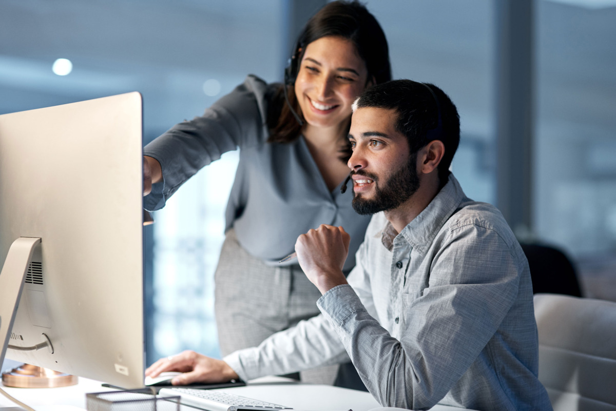 Two people sitting at a computer supporting one another